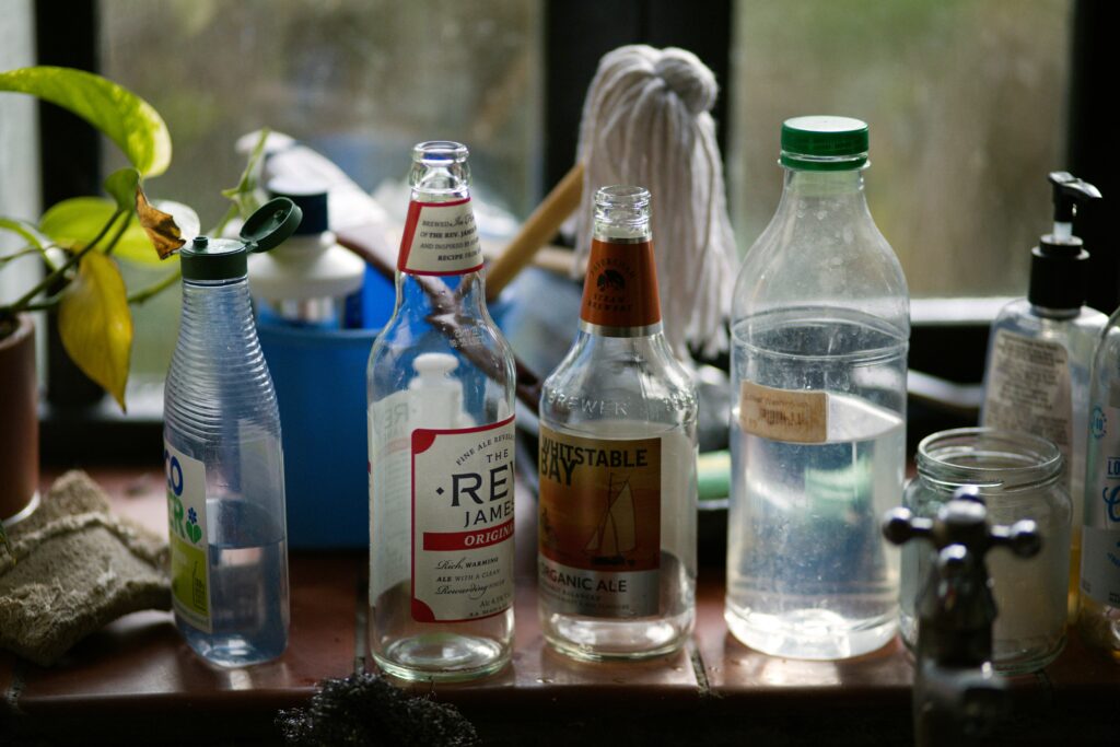 A collection of empty glass bottles and plastic containers on a kitchen countertop.