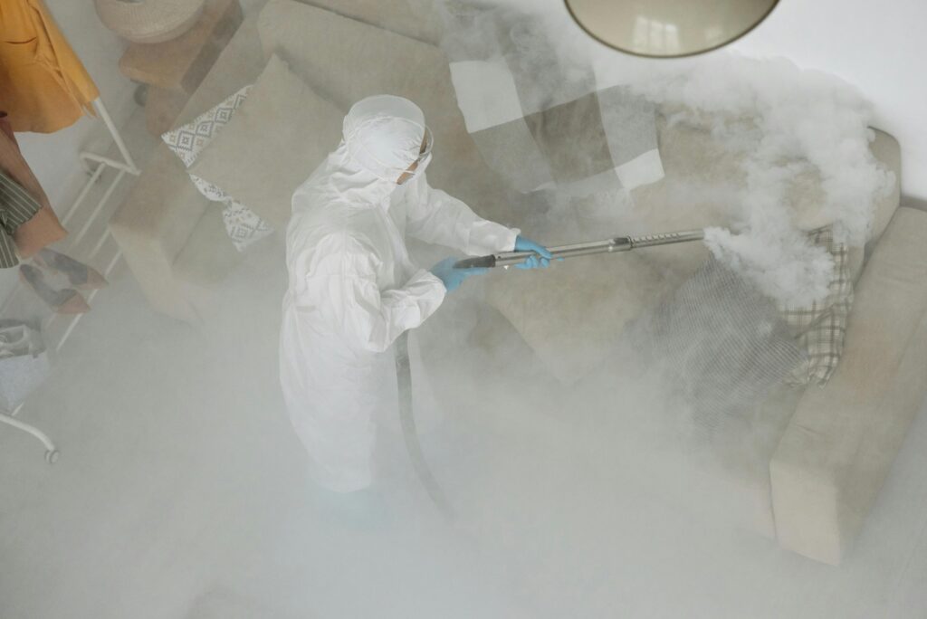 Pure Space Home Cleaning Services Technician in protective gear sanitizing a living room with smoke fumigation.