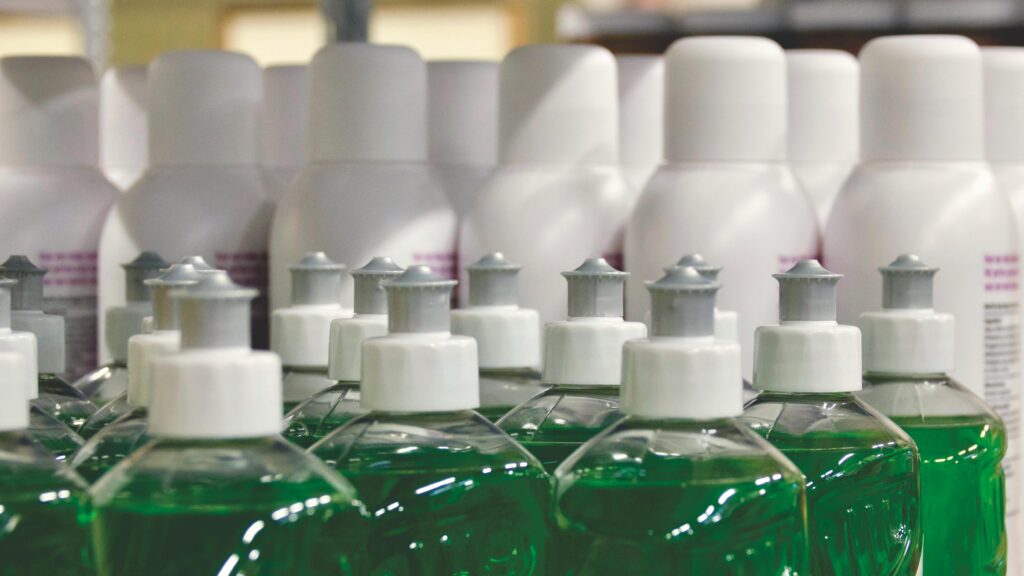 Healthier Spaces Close-up view of green liquid in bottles, ideal for household cleaning and stocks.