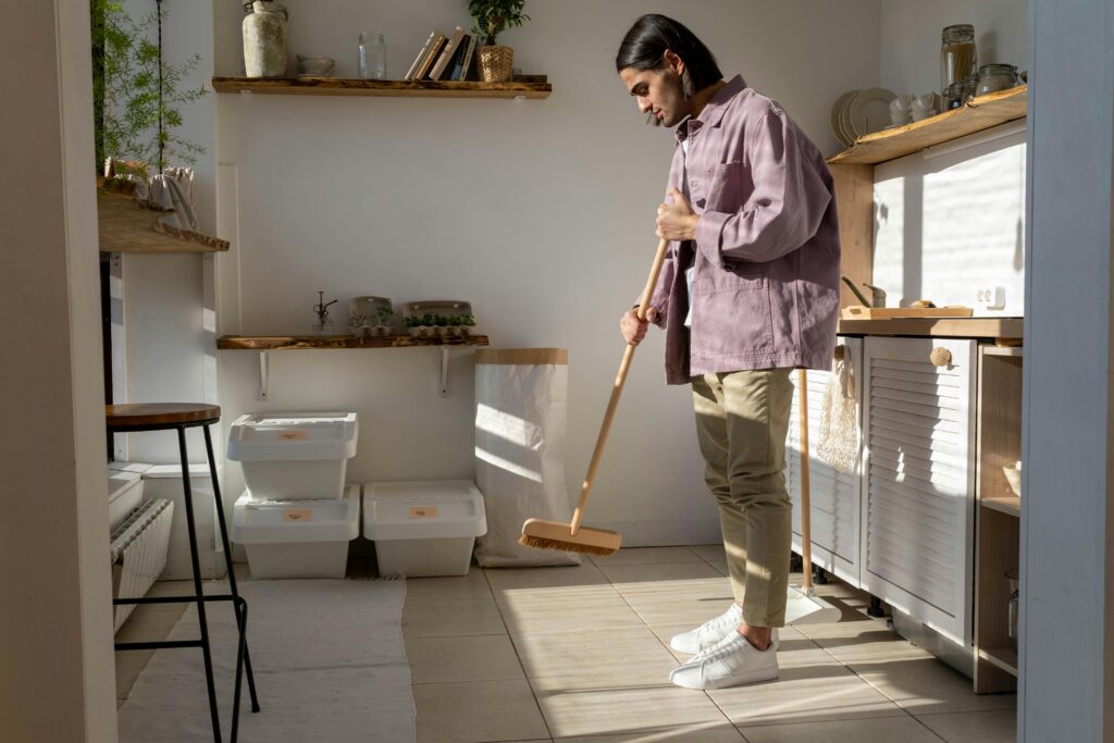 A man in casual attire cleans a stylish kitchen, emphasizing eco-friendly living.